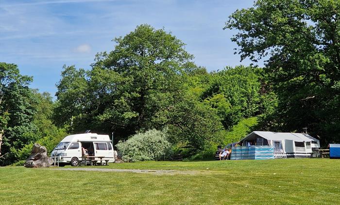 Camper van and tent on grass pitch with EHU